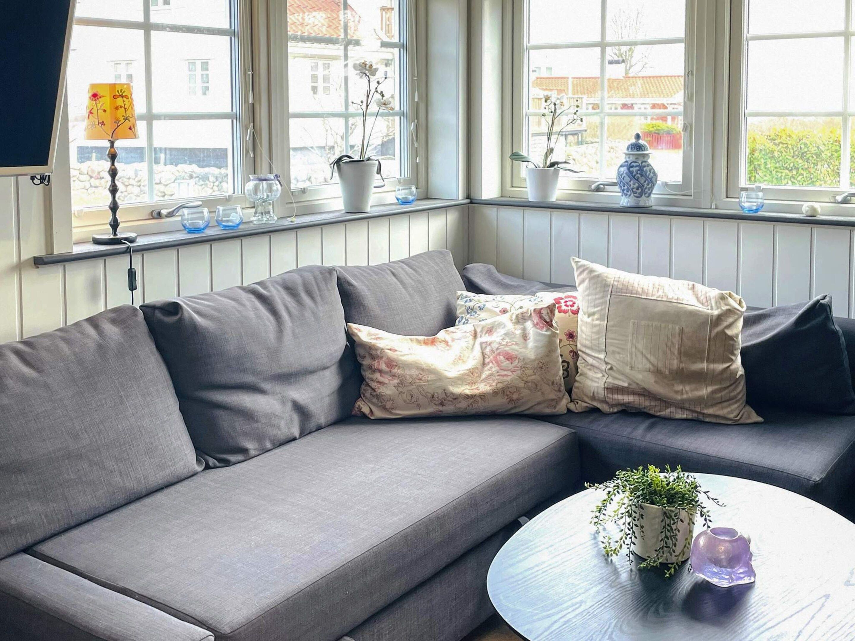 A modern living room with a grey sofa, a round coffee table, and a window with a view of buildings.