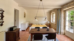 Ein Zimmer mit Bett, Tisch mit Stühlen, Lampe, Heizkörper und einem Fenster mit Vorhängen.