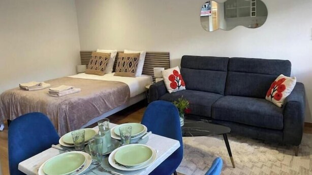 Et hotelværelse med seng, sofa, spisebord med tallerkener og glas samt et spejl på væggen.