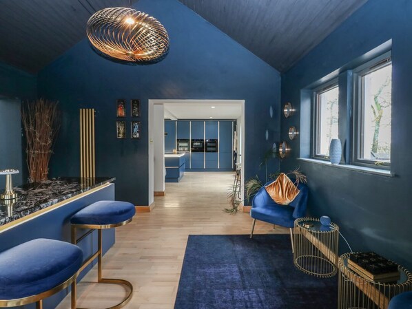 A modern interior with a bar area, seating, and a view through a doorway.