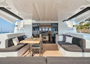 A yacht interior with a dining area, two sofas, a table, and a kitchen. - Sun-Kissed Sailing Adventure in Islas Sarónicas (Alimos)