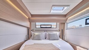A modern, well-lit bedroom with a skylight, a bed with multiple pillows, and a view of the outside. - Sun-Kissed Sailing Adventure in Islas Sarónicas (Alimos)