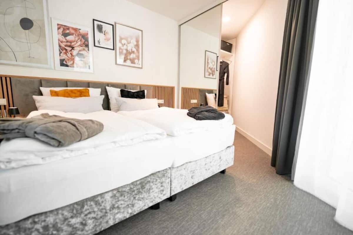 Una habitación de hotel moderna con una cama grande, un espejo y obras de arte en las paredes.
