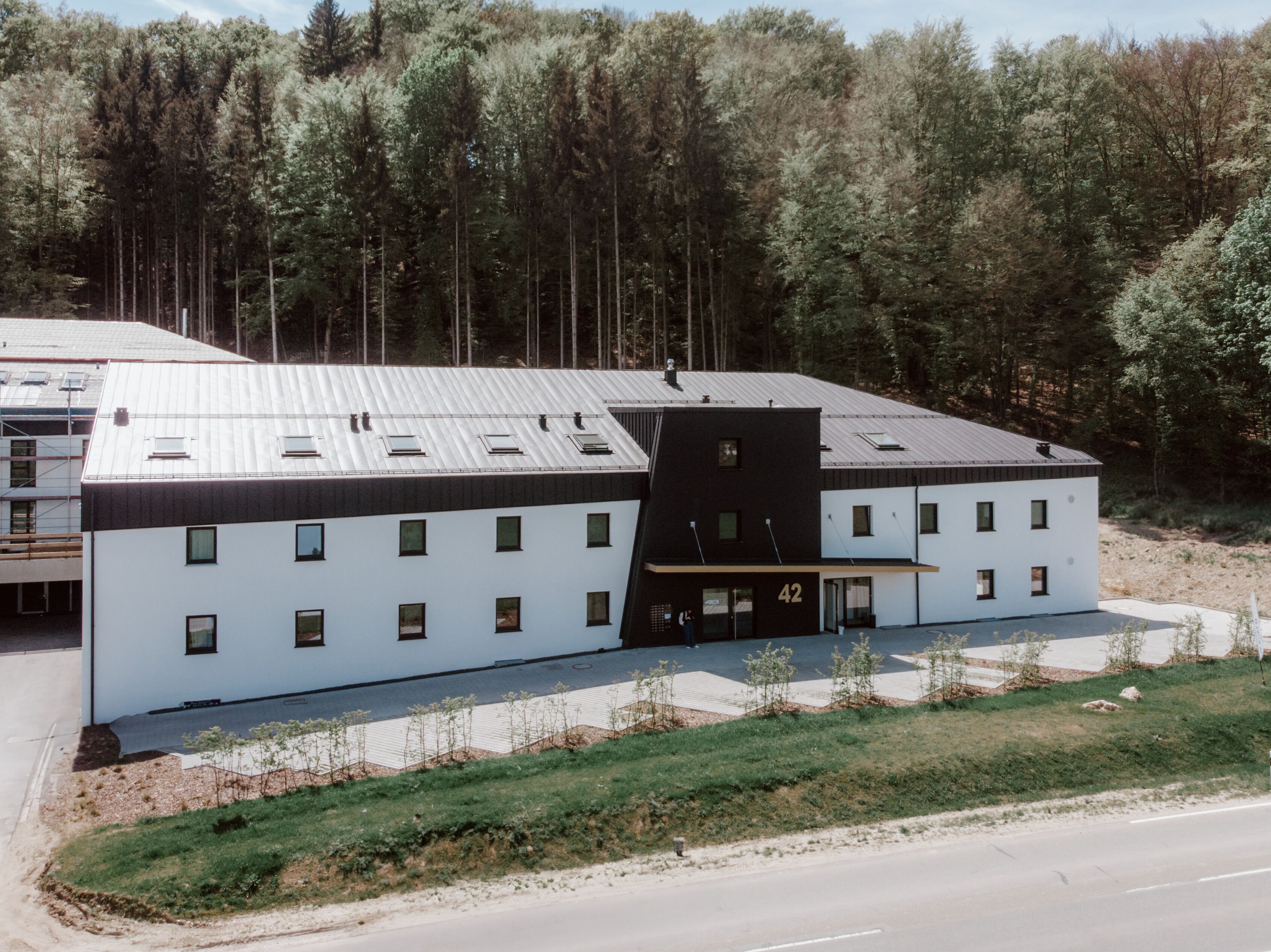 A modern building with a flat roof, multiple windows, and a distinct black section.