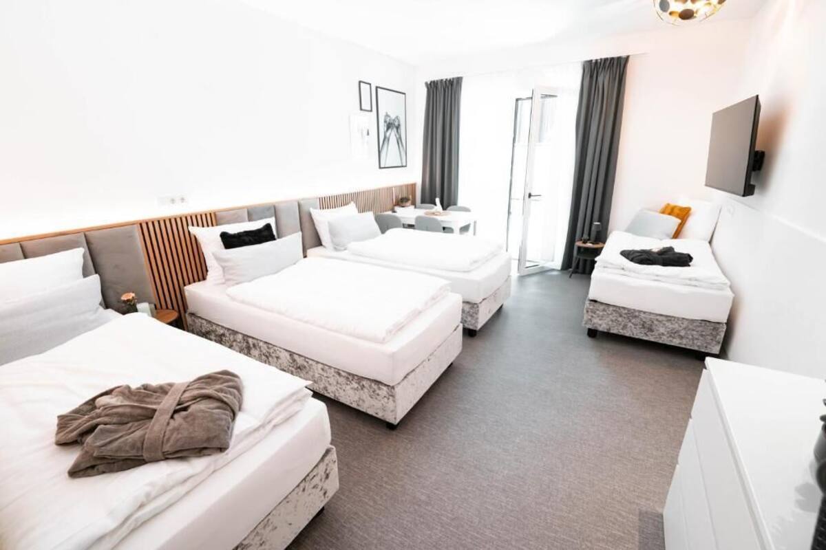 Habitación de hotel con tres camas, un escritorio y una televisión.