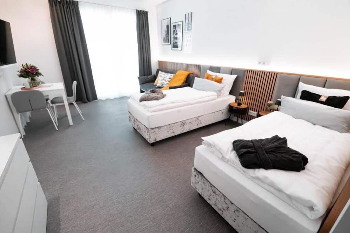 Habitación de hotel con dos camas, un escritorio y una silla.