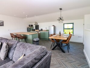 A modern kitchen with a dining area, a sofa, and a window with a view.