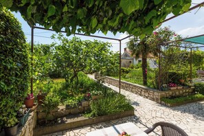 A garden with stone pathways, potted plants, and a pergola structure. - Vacation home in Jadranovo with a Mediterranean garden and balcony (Jadranovo)