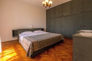 A bedroom with a bed, a bedside table, a wardrobe, and a chandelier. - Vacation home in Jadranovo with Mediterranean garden & balcony (Jadranovo)