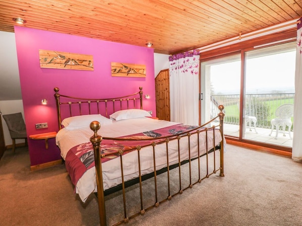 Une chambre à coucher avec un lit, un plafond en bois, des murs roses et un balcon avec des chaises.