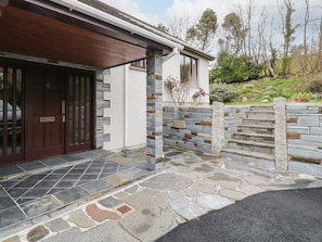 Un bâtiment moderne doté d’une façade en pierre, d’une porte en bois et d’un escalier en pierre menant à l’entrée.