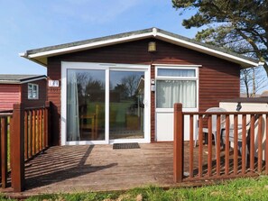 A single-story building with a wooden deck, a sliding glass door, and a small porch area.