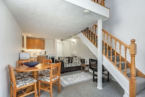 A compact living space with a dining area, kitchen, and a staircase.