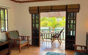 Una habitación con piso de madera, una mesa con sillas, un sofá y una ventana con vistas a zonas verdes.