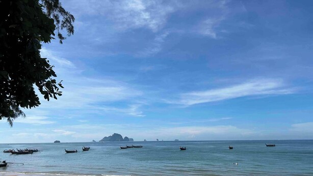 Ein Strand mit Booten, klarem Wasser und in der Ferne Inseln.