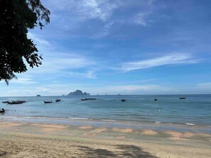 Une plage avec des bateaux, une eau cristalline et des îles à l’horizon.