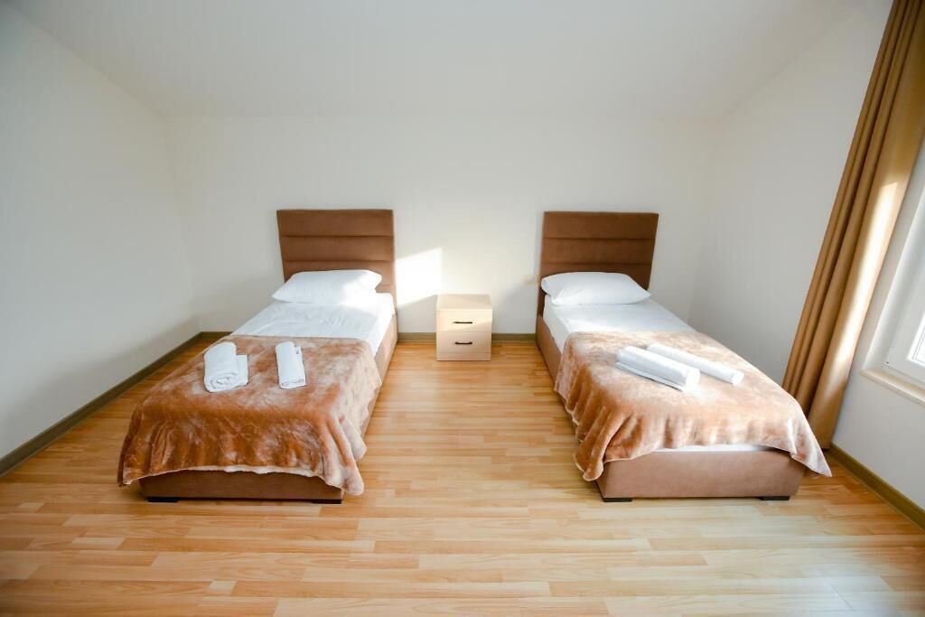 A twin room with two beds, wooden flooring, and a small bedside table.