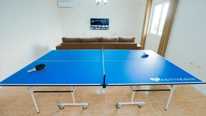 Ein Pingpongtisch mit einem Fernseher im Hintergrund.