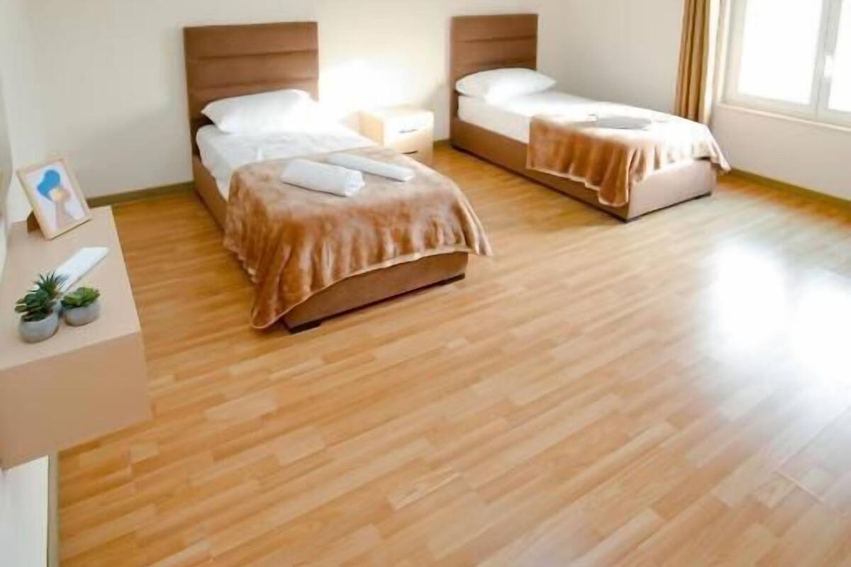 A room with two beds, a small table, and a window.