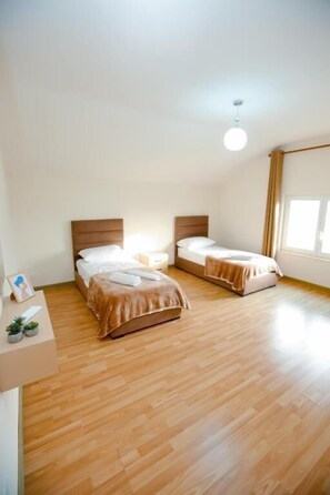 Een kamer met twee bedden, een klein tafeltje en een raam.