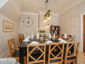A dining room with a clock, wooden chairs, a black table, and a hanging light fixture. - Verdo House, Blackpool (Blackpool)