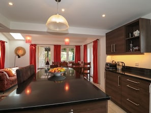 A modern kitchen with a central island, wooden cabinets, and a dining area with red curtains.