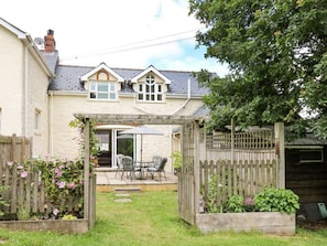 A house with a patio, a wooden fence, and a garden.