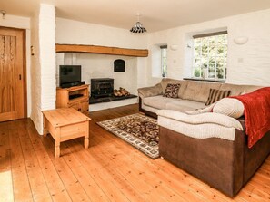 A cozy living room with a sofa, a television, a fireplace, and a wooden floor.