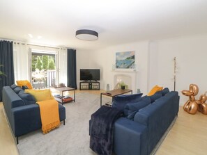 Un salon comprenant un canapé, un téléviseur, une cheminée et un tableau accroché au mur.