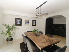 Un comedor moderno con una mesa de madera, sillas, una planta en maceta y obras de arte en la pared.