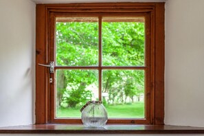 A window with a clear view of greenery outside. - Old Smiddy Cottage, Haddington (Dunbar)