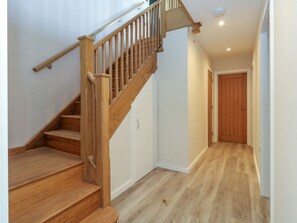 A wooden staircase with a handrail, a door at the top, and a hallway with wooden flooring.