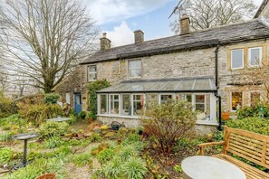 A stone house with a conservatory, a garden with various plants, and a bench. - IVY COTTAGE, WiFi, Woodburner, Snug room, Buxton (Buxton)