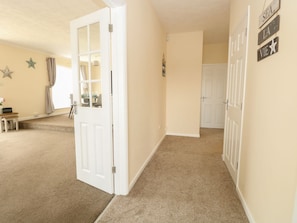A hallway with beige walls, a carpeted floor, and a white door.