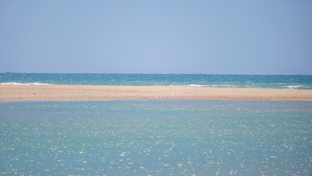 Een strand met helder water en een zandstrand.