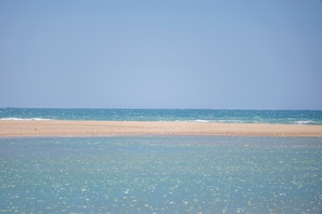 Een strand met helder water en een zandstrand.