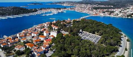 An aerial view of a coastal town with a marina, dense residential area, and a curved coastline.