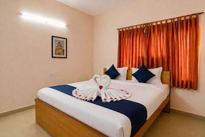 Habitación de hotel con una cama bien hecha, un cuadro en la pared y una ventana con cortinas naranjas.