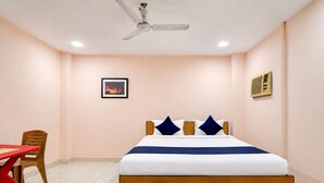 Ein Hotelzimmer mit Bett, Deckenventilator, einem Bild an der Wand und einem Tisch mit Stuhl.