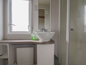 Ein Badezimmer mit Fenster, Waschbecken, Spiegel und Dusche.