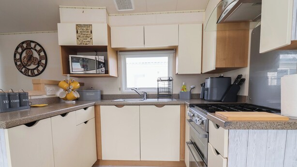 Una cocina compacta con microondas, estufa, fregadero y armarios de madera.