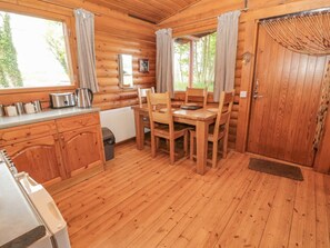 Eine Holzhütte mit Esstisch, Stühlen, einem Wasserkocher und einer Heizung.