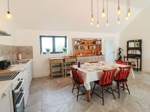 Una cocina con una mesa de comedor para cuatro personas, una estantería y un espejo con iluminación.