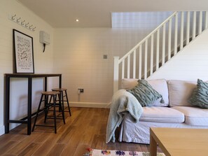 Uma sala de estar com escada, um sofá, uma mesa de centro e um quadro na parede.