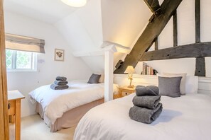 Un dormitorio con dos camas, una viga de techo de madera, una lámpara de noche y una ventana con vistas.