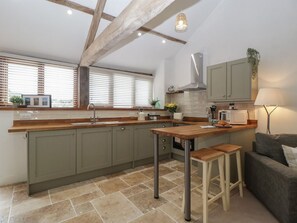 Una cocina moderna con una isla central, vigas de madera y vistas amplias por grandes ventanales.