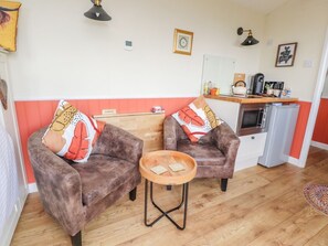 A cozy living room with two brown armchairs, a small wooden table, and a kitchenette in the background. - The Journeyman, Barnoldswick (Barnoldswick)