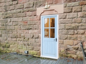 A light blue door with a window, set in a stone wall with a small light fixture above.