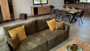 A modern living room with a sofa, dining table, and kitchen area. - Villa 6 persons with swimming pool and large garden near Porto-Vecchio (Zonza)