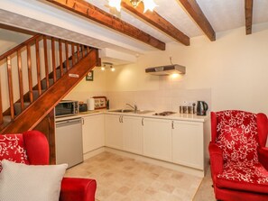 Una cocina con armarios blancos, una escalera de madera y un sillón rojo.
